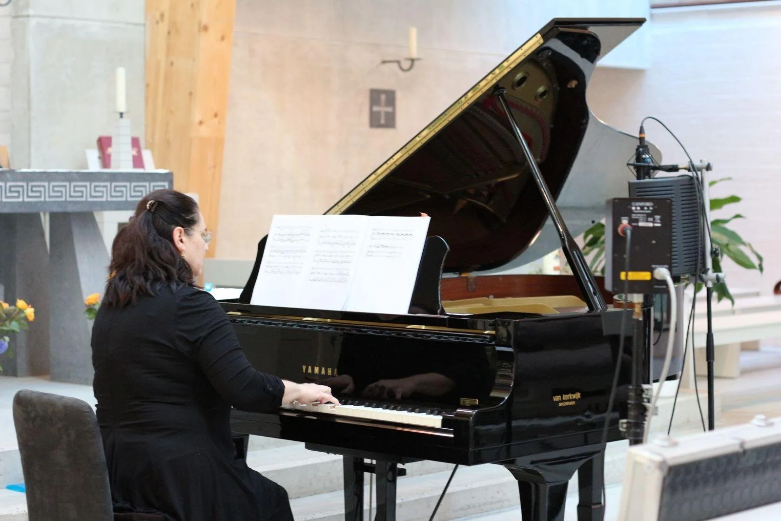 Evelina speelt van bladmuziek aan een vleugel, met opnamemicrofoons in de buurt